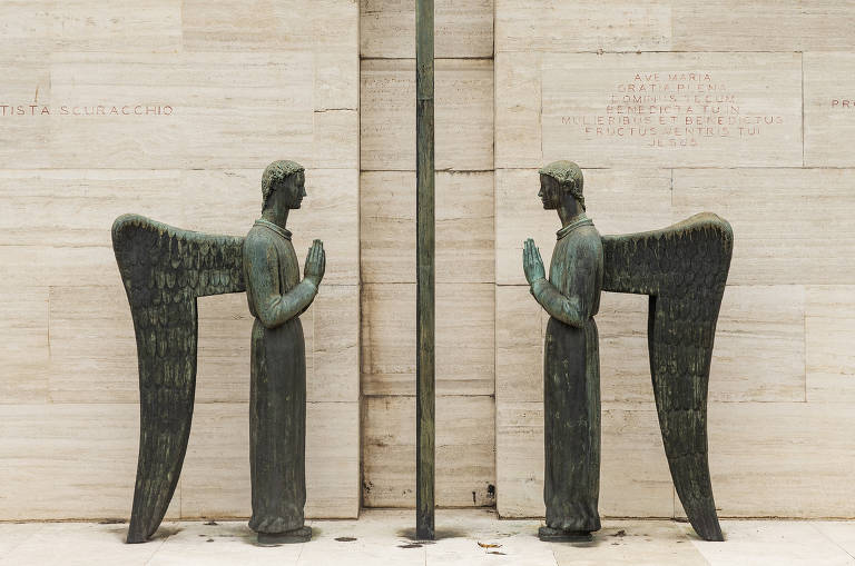 Esculturas de dois anjos de frente um para o outro na entrada de um mausoléu