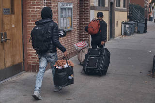 A Venezuelan migrant, at left, departing from a migrant assistance center at St. Brigit Elementary School as to look for a new shelter, in New York on Oct. 26, 2023.  (Andrés Kudacki/The New York Times)