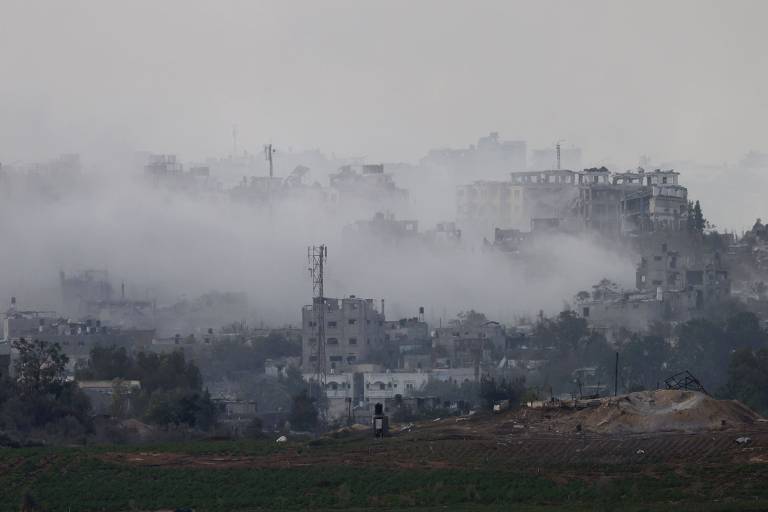 Escombros de prédios bombardeados são visto em meio a fumaça na Faixa de Gaza