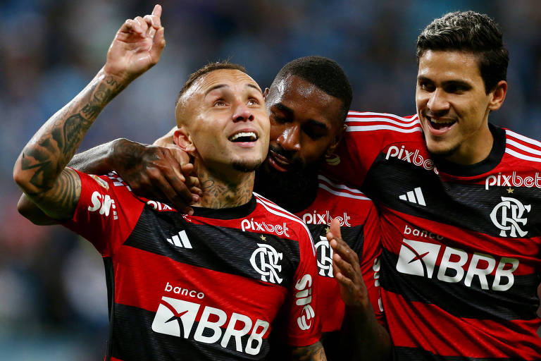 Três jogadores de futebol do Flamengo comemoram gol