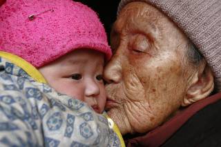 An elderly woman kisses a three-month-old baby at a village in Suining