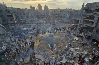 Palestinians search for casualties at the site of Israeli strikes on houses in Jabalia refugee camp