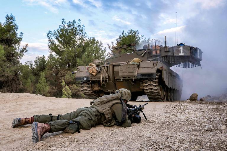 Soldado israelense deitado próximo a tanque na fronteira norte de Israel com o Líbano