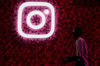 A man walks past a logo of mobile application Instagram, during a conference in Mumbai