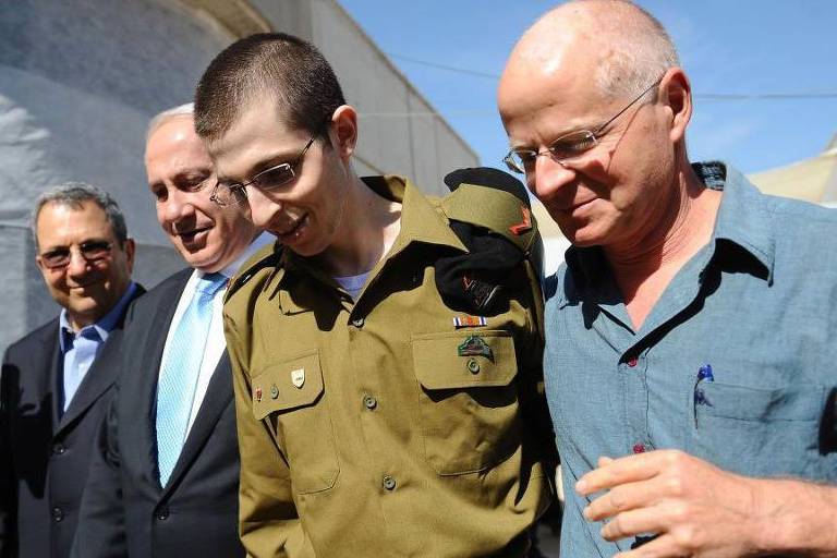 Gilad Sahlit, com seu pai Naom (à direita), e o então ministro da Defesa israelense, Ehud Olmert, e o primeiro-ministro Benjamin Netanyahu, foi libertado pelo Hamas em troca de 1.027 prisioneiros palestinos