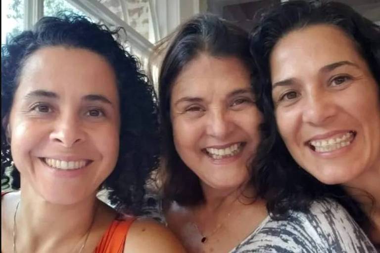 Em foto colorida, três mulheres posam sorridentes para foto