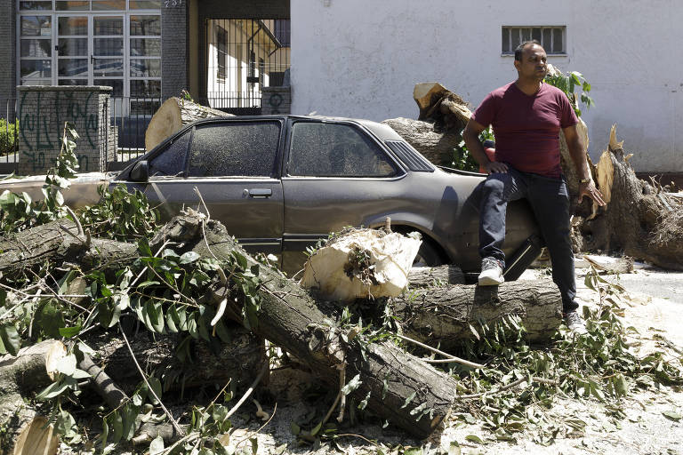 Vigilante Ismael Pimentel dos Santos, 47, ao lado de seu Chevette 1986 destruído por queda de árvore na Vila Clementino, zona sul de São Paulo 
