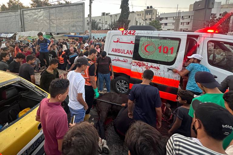 Moradores ao redor de uma das ambulâncias do comboio alvo de ataque aéreo na Cidade de Gaza, a mais populosa da faixa homônima