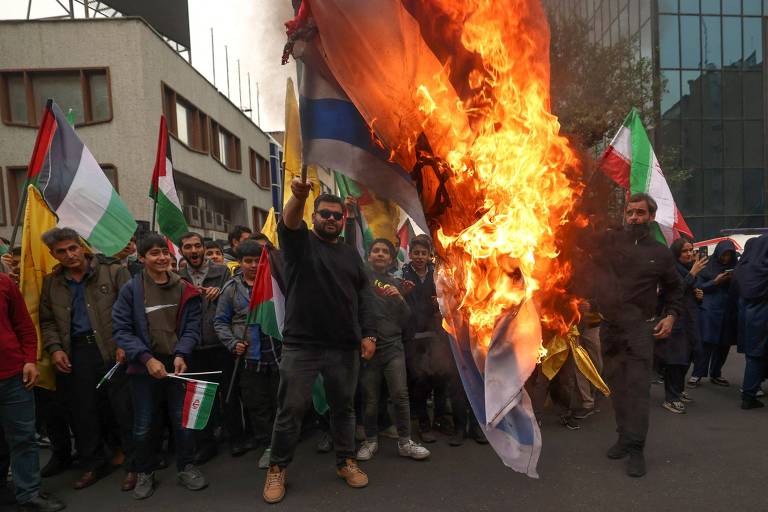 Manifestantes queimam bandeira de Israel em frente à antiga embaixada dos EUA em Teerã, em protesto para marcar os 44 anos da crise dos reféns americanos no local, após a Revolução Islâmica 