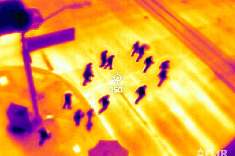 Foto de câmera de calor mostra pessoas como pontos pretos em meio a uma superfície amarela, que é a rua