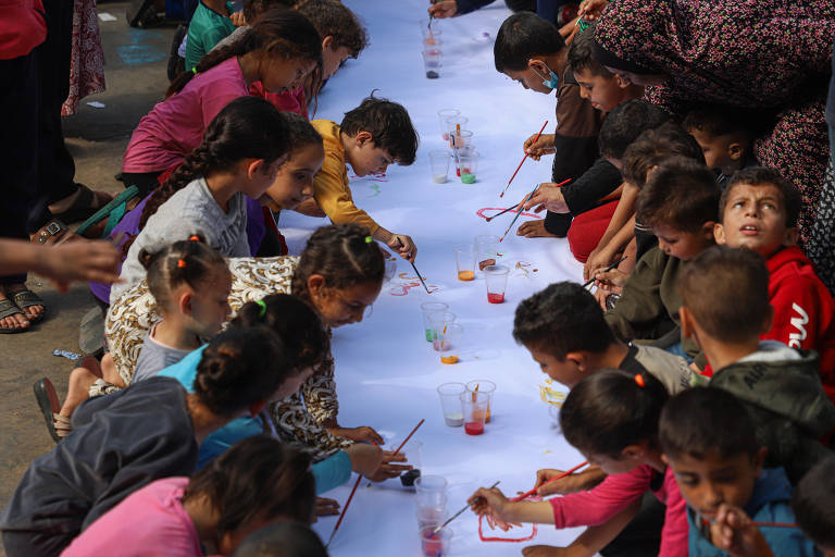 Crianças na Faixa de Gaza fazem desenhos em um cartaz