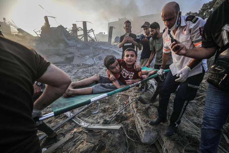 Imagem de duas crianças sendo socorridas em maca após ataque israelense na Faixa de Gaza