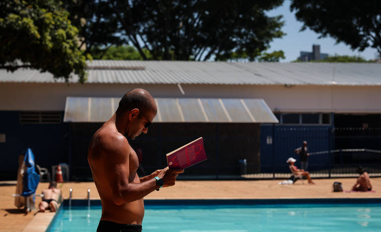 Rapaz lê à beira da piscina do Centro Esportivo Ibirapuera