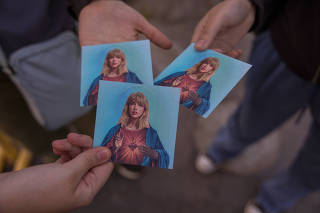 Maria Claude Arzapalo and her friends hold cards showing Taylor Swift depicted as Jesus, the night before Taylor SwiftÕs Eras Tour at El Monumental Stadium in Buenos Aires, Argentina, Nov. 8, 2023. (Sarah Pabst/The New York Times)