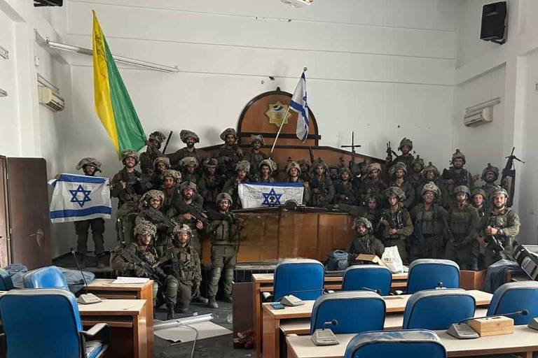 Soldados da brigada de elite Golani posam com bandeiras de Israel no Parlamento de Gaza