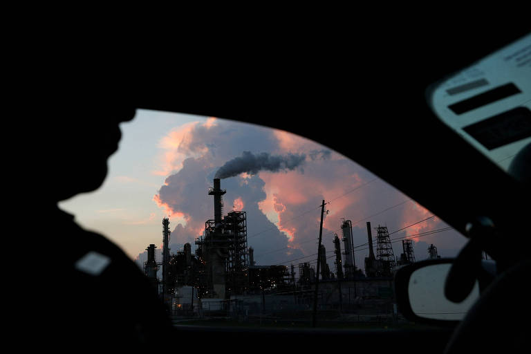 Um oficial de política dirige à frente de uma refinaria industrial de petróleo, em Pasadena, no Texas