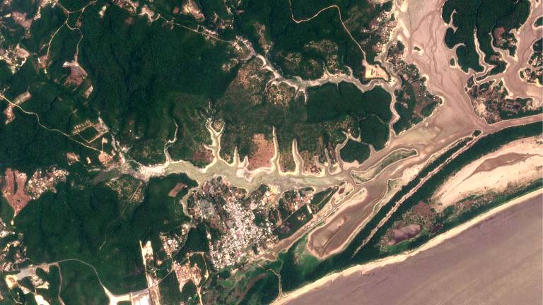foto aérea mostra bancos de areia em rio quase seco, com água barrenta do lado direito da imagem e área urbanizada no centro, na parte inferior