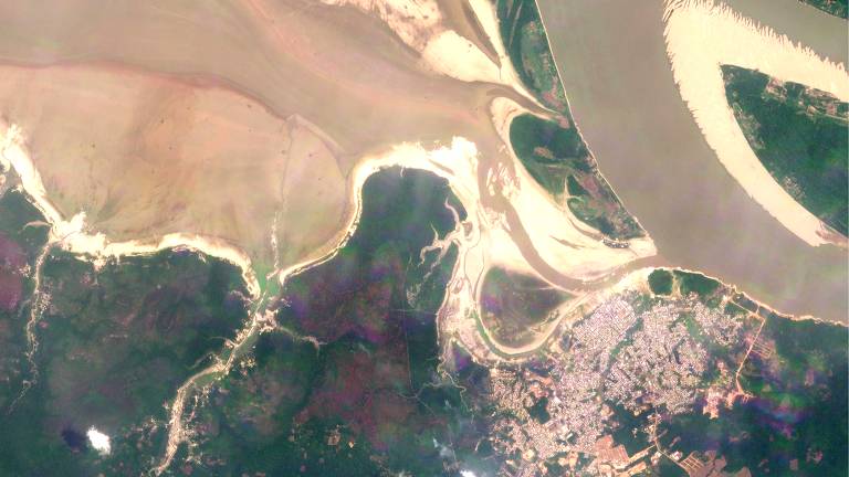 foto de satélite mostra leito de rio seco, com água barrenta em algumas partes, e bancos de areia com grande extensão. no canto inferior direito, área urbanizada