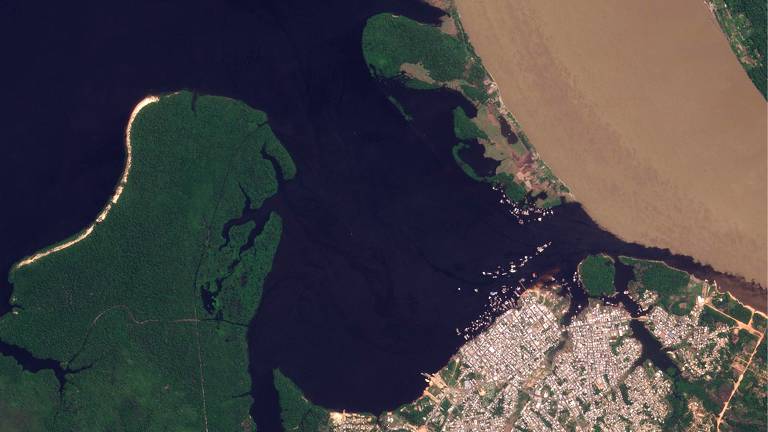foto aérea mostra leito de rio ao centro da imagem, à esquerda área verde, no canto inferior à direita área urbanizada