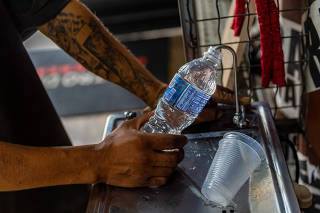 Usuário enche garrafas de água no Teatro Container Mugunzá
