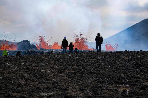 (FILES) In this file photo taken on August 04, 2022 people visit the scene of the newly erupted volcano taking place in Meradalir valley, near mount Fagradalsfjall, Iceland. - The flow of lava from the small crater at Meradalir in Iceland, where a volcanic eruption has been underway since August 3, has 