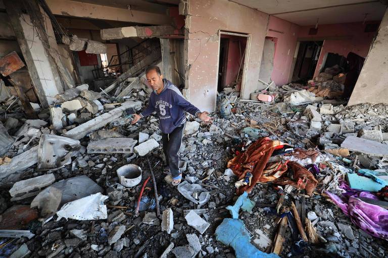 Palestino em ruína de prédio atingido por Israel em Khan Yunis, cidade que concentra famílias brasileiras em Gaza