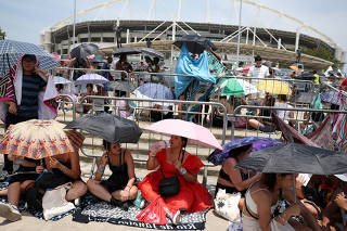 People holding umbrellas wait for the  Taylor Swift concert, in Rio de Janeiro