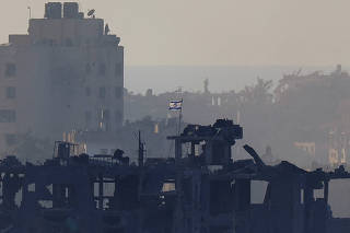 An Israeli flag flutters on a destroyed building in Gaza, as seen from southern Israel