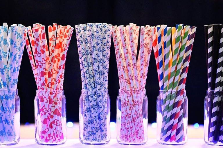 Recipientes de vidro contendo canudos de papel coloridos com diferentes estampas
