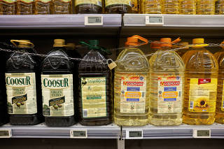 Olive and sunflower oil bottles are displayed for sale, protected by a padlock and a chain to prevent theft in a Tu Super Suma supermarket in Malaga