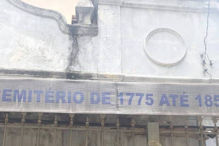  Toldo em fachada de igreja que diz "Cemitério de 1775 até 1858" 