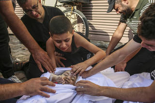 Khaled Joudeh, mourns over the body of his baby sister, Misk, in Deir al Balah, Gaza, on Sunday, Oct. 22, 2023. (Samar Abu Elouf/The New York Times)