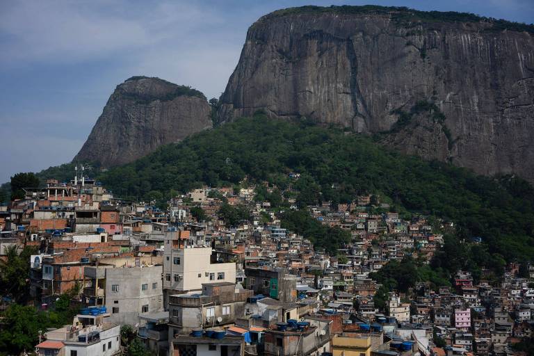 Vista do topo da Rocinha. A imagem mostram casas de favela construídas em topo do morro, cercada por mata 