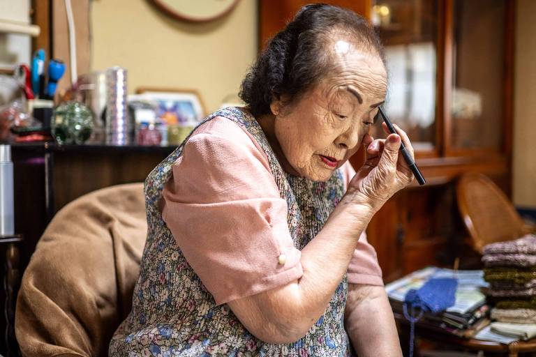 Tomoko Horino usa um lápis de olho para se maquiar em sua casa no Japão
