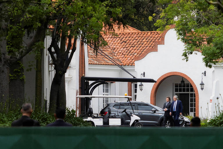 O incumbente Alberto Fernández e o presidente eleito da Argentina, Javier Milei, caminham na Quinta de Olivos, residência oficial da Presidência, em encontro nesta terça (21)