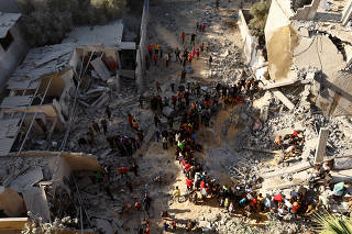 Palestinians gather as others search for casualties at the site of an Israeli strike, amid the ongoing conflict between Israel and Palestinian Islamist group Hamas, in Khan Younis