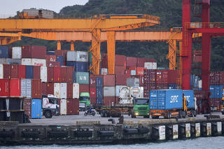 FILE PHOTO: Cargo trucks work inside a container yard, in Keelung