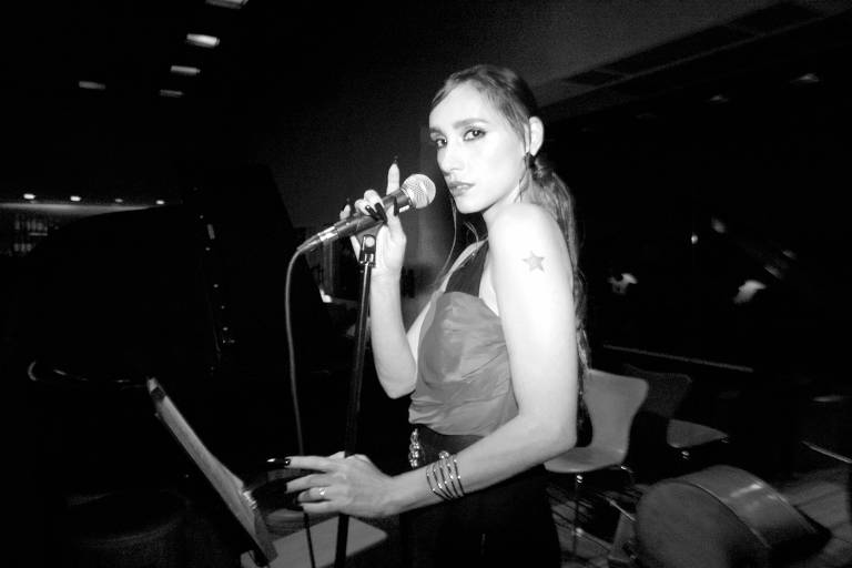 Em foto preto e branco, a cantora Lia Paris aparece cantando