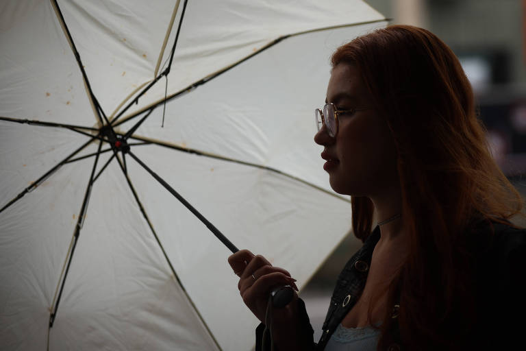 Mulher se protege da chuva com uma sombrinha