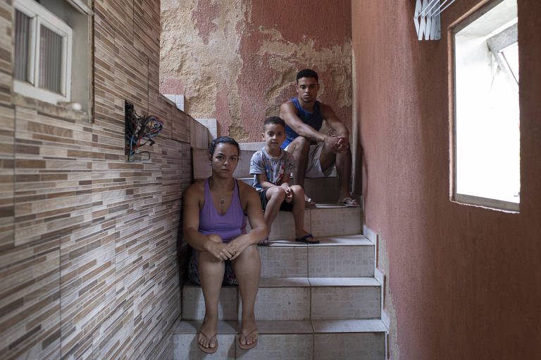 Três pessoas sentadas em uma escada interna de uma casa