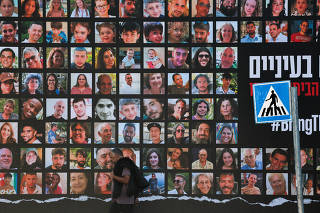 A man walks past an installation with pictures of hostages taken by Palestinian Islamist group Hamas, in Jerusalem