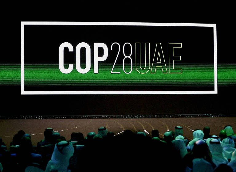 Logo da COP28 é exibida em telão em sala de conferências
