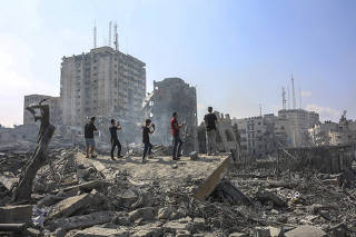People look over damage from Israeli airstrikes in central Gaza City, Oct. 10, 2023.  (Samar Abu Elouf/The New York Times)