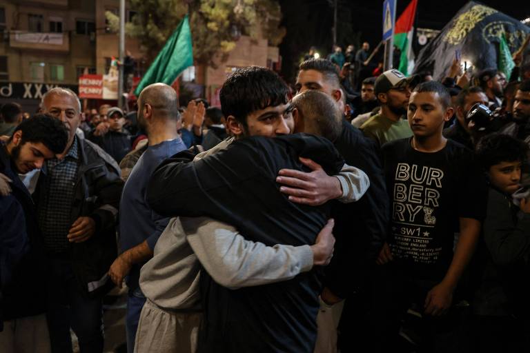 Dois homens se abraçam em meio a multidão com bandeiras verdes