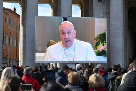 Faithfuls gather to attend the Angelus prayer on a screen, led by Pope Francis in St. Peter's Square at the Vatican on November 26, 2023. The pontiff did not recite from the window of the apostolic palace due to a flu condition. (Photo by Alberto PIZZOLI / AFP)