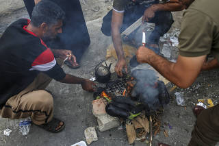 Palestinians cook eggplants on a street in Khan Younis, Gaza, on Oct. 29, 2023. (Samar Abu Elouf/The New York Times)