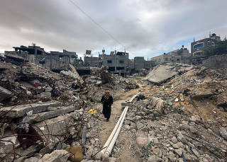 Palestinians inspect houses, destroyed in Israeli strikes during the conflict, at Khan Younis refugee camp