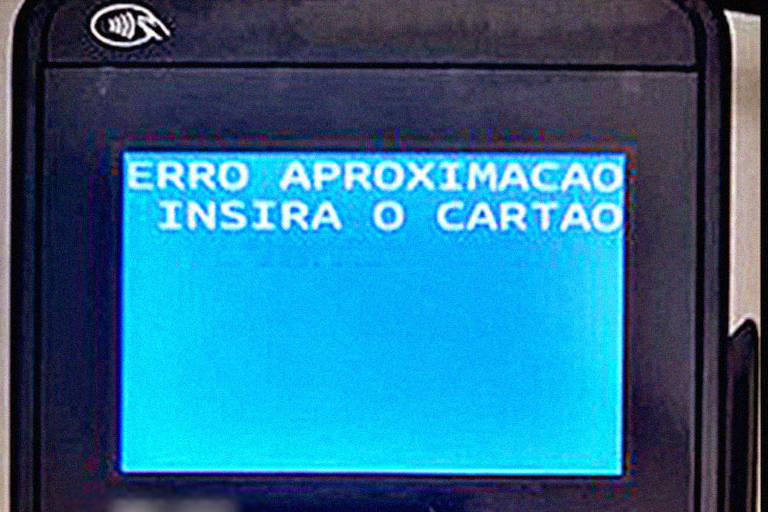 Máquina de cartão é vista de cima, com mensagem na tela dizendo "erro aproximação. Insira o cartão".