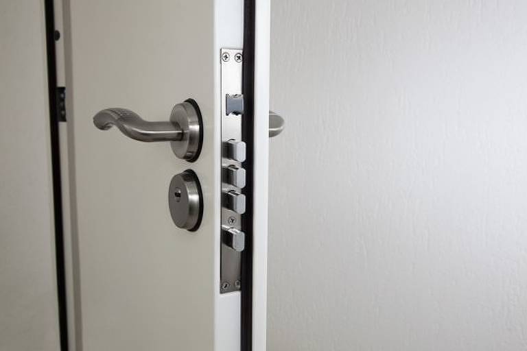 A imagem mostra uma porta branca; a fechadura possui quatro travas