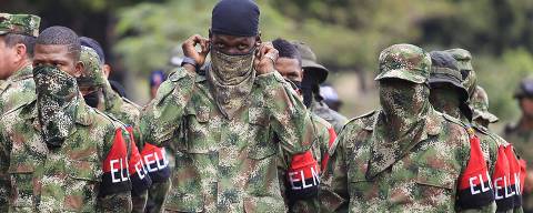 A defected member of Colombian guerrilla group ELN adjusts his scarf as he falls in with his comrades after their surrender and the handover of their weapons at a military base in Cali July 16, 2013. Authorities said 30 rebels from Colombia's second-biggest guerrilla group, the National Liberation Army (ELN), demobilized on Tuesday in El Tambo municipality in Cauca due to military pressure in the area. REUTERS/Jaime Saldarriaga  (COLOMBIA - Tags: POLITICS MILITARY CIVIL UNREST) ORG XMIT: JS05